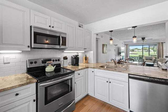 kitchen with white cabinetry, sink, light stone counters, and stainless steel appliances