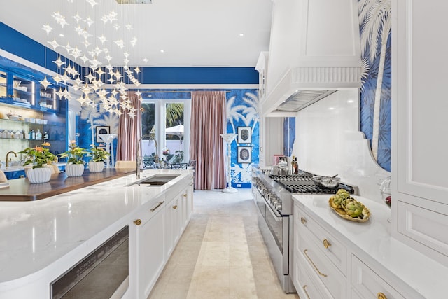 kitchen with pendant lighting, sink, stainless steel stove, and white cabinets