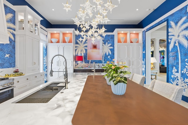 kitchen with light stone countertops, sink, white cabinets, and decorative light fixtures