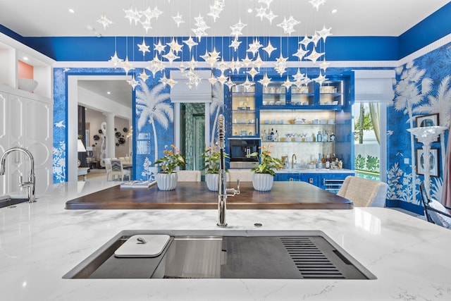 kitchen featuring light stone countertops, sink, and decorative light fixtures