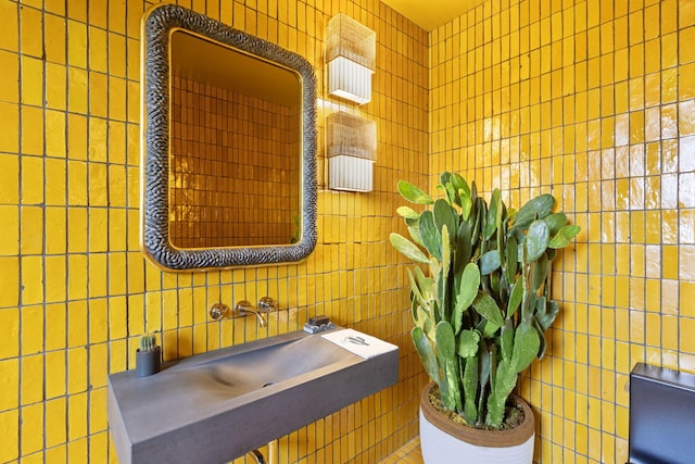 bathroom featuring sink and tile walls