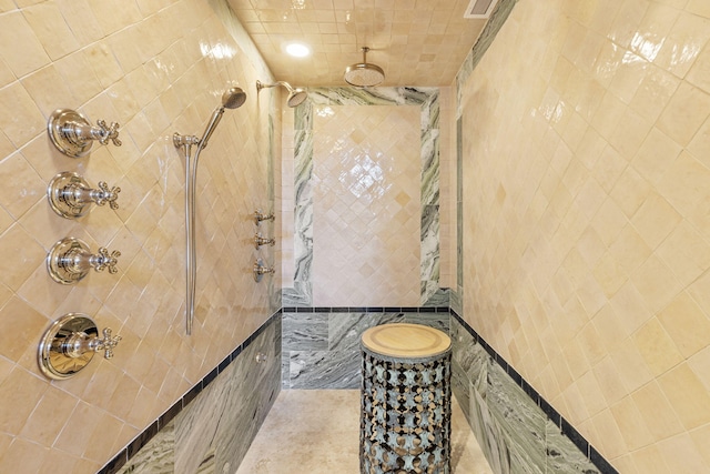 bathroom featuring tiled shower and tile walls