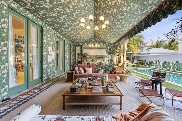 sunroom with vaulted ceiling, a notable chandelier, and french doors