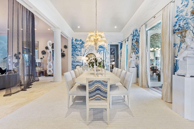 dining room with crown molding, a chandelier, a raised ceiling, and decorative columns