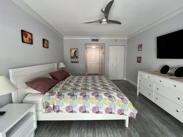 bedroom with a textured ceiling, ornamental molding, dark hardwood / wood-style flooring, a closet, and ceiling fan