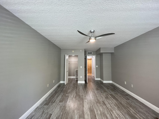 interior space featuring dark hardwood / wood-style flooring, a walk in closet, ceiling fan, a textured ceiling, and a closet