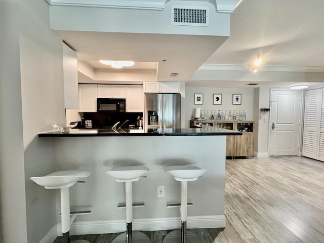 kitchen with white cabinetry, a tray ceiling, kitchen peninsula, and stainless steel refrigerator with ice dispenser