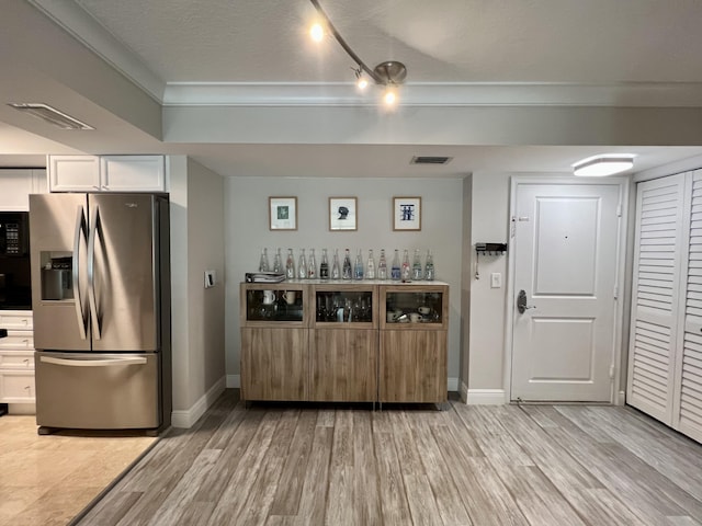 kitchen with stainless steel refrigerator with ice dispenser, white cabinetry, a textured ceiling, and light wood-type flooring