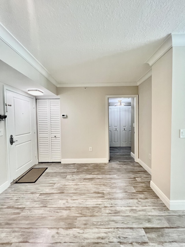 entryway featuring crown molding, a textured ceiling, and light wood-type flooring