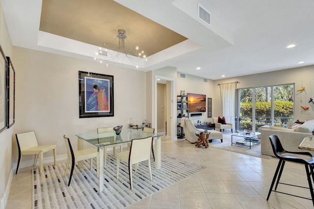 dining area with a tray ceiling, light tile patterned flooring, and a notable chandelier