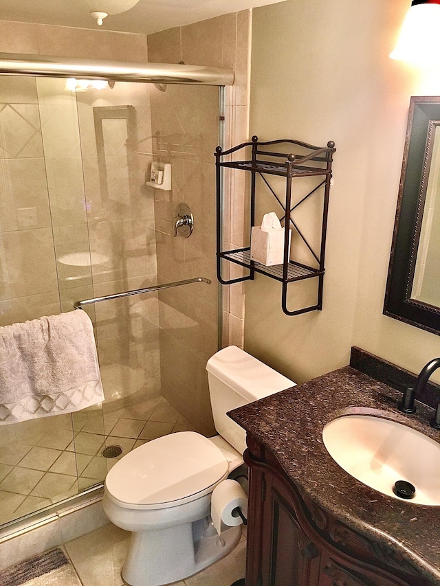 bathroom featuring tile patterned floors, vanity, a shower with shower door, and toilet