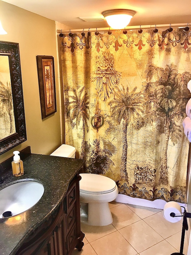 bathroom with toilet, vanity, and tile patterned floors