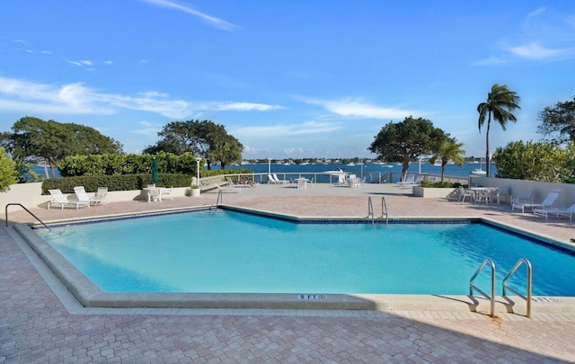 view of swimming pool featuring a patio area and a water view