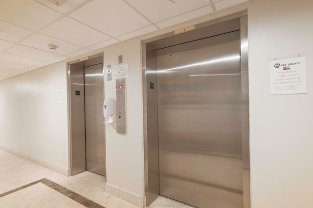 interior space featuring light tile patterned floors, elevator, and a drop ceiling