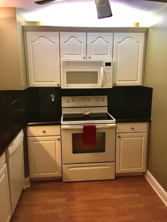 kitchen featuring white cabinets, light wood-type flooring, and white appliances