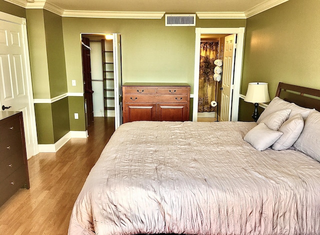 bedroom featuring wood-type flooring, crown molding, and a closet