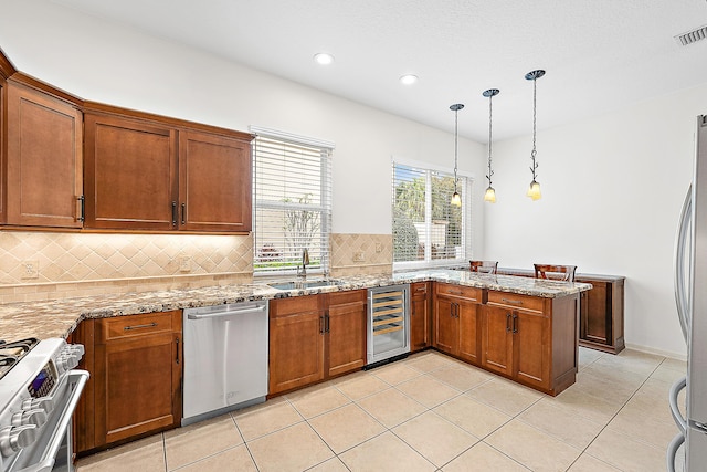 kitchen with wine cooler, light stone counters, appliances with stainless steel finishes, pendant lighting, and a sink