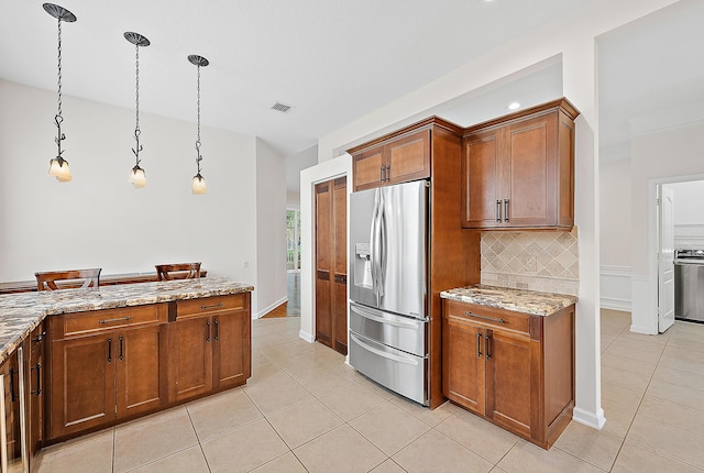 kitchen featuring visible vents, stainless steel refrigerator with ice dispenser, light stone countertops, tasteful backsplash, and decorative light fixtures