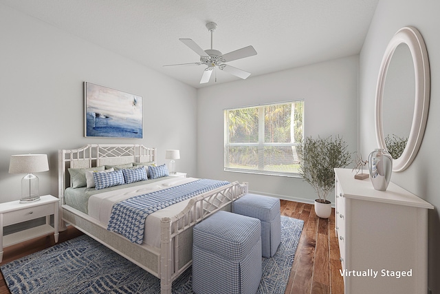 bedroom featuring a textured ceiling, dark wood-style flooring, a ceiling fan, and baseboards