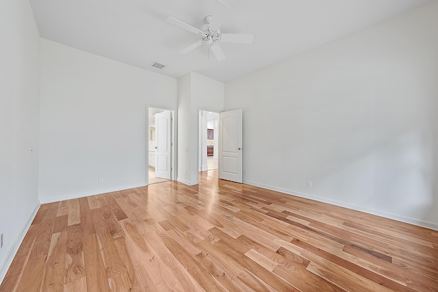 interior space featuring light wood finished floors, baseboards, visible vents, a ceiling fan, and ensuite bath