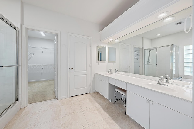 bathroom featuring double vanity, a stall shower, and a sink