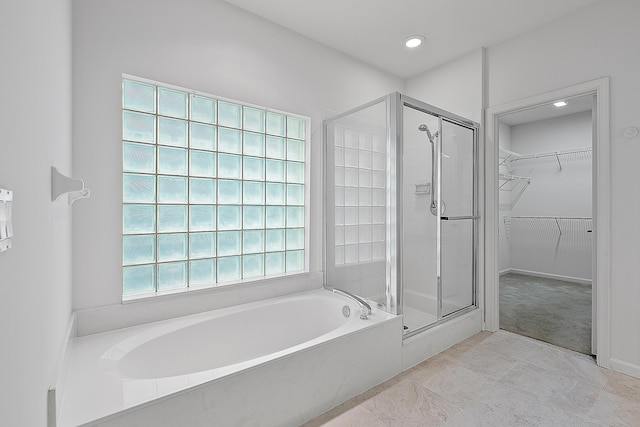 bathroom featuring a stall shower, a garden tub, and a spacious closet