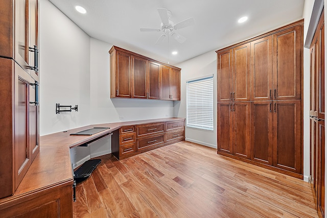 office space featuring light wood finished floors, built in desk, and recessed lighting