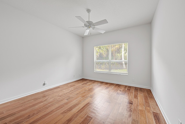 spare room featuring light wood finished floors, ceiling fan, baseboards, and a textured ceiling