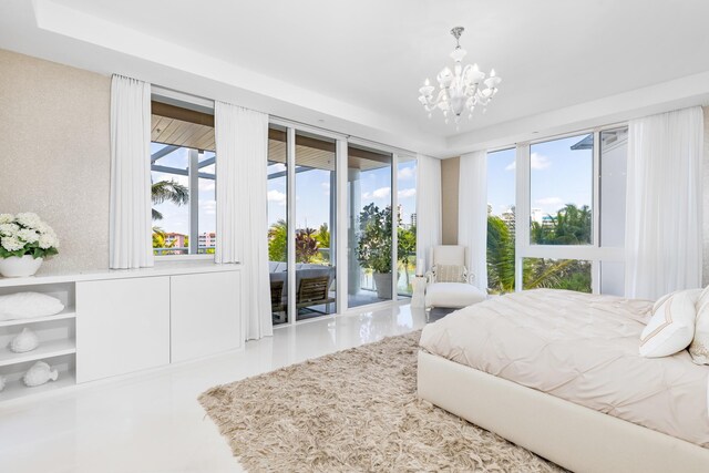 bedroom featuring a tray ceiling, access to exterior, and a notable chandelier