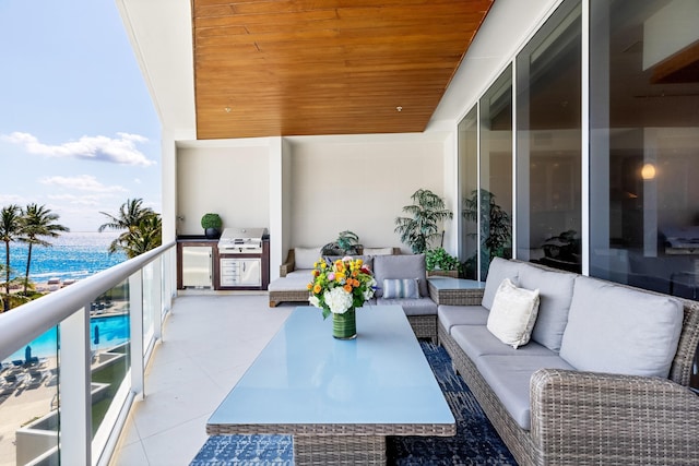 balcony featuring grilling area, an outdoor hangout area, a water view, and exterior kitchen