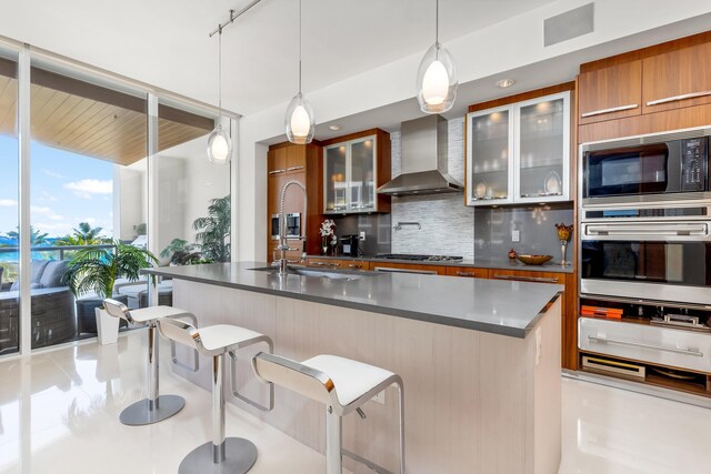 kitchen with tasteful backsplash, wall chimney exhaust hood, stainless steel appliances, and a kitchen bar