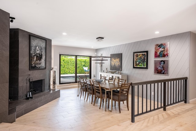 dining room with a tile fireplace and light wood-type flooring