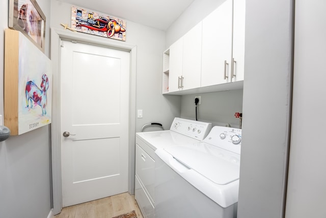 clothes washing area with washing machine and dryer, cabinets, and light hardwood / wood-style floors