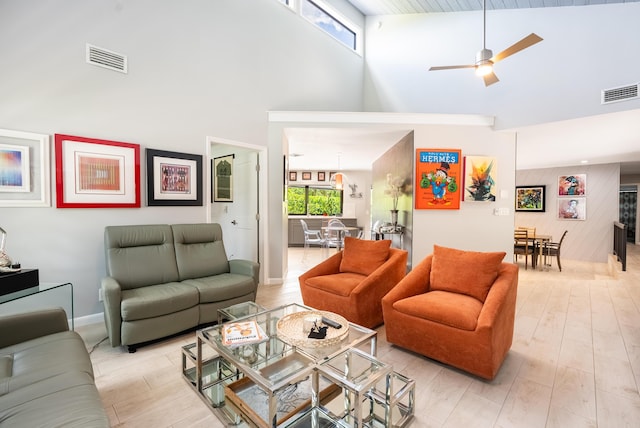 living room featuring light hardwood / wood-style flooring, high vaulted ceiling, ceiling fan, and a healthy amount of sunlight