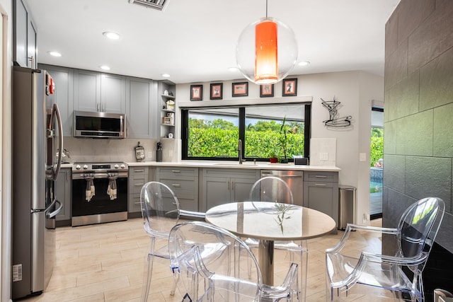 kitchen with gray cabinets, sink, stainless steel appliances, and light hardwood / wood-style flooring