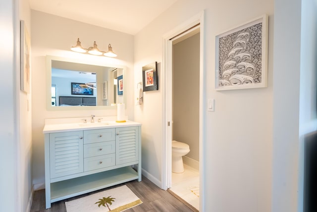 bathroom with wood-type flooring, vanity, and toilet