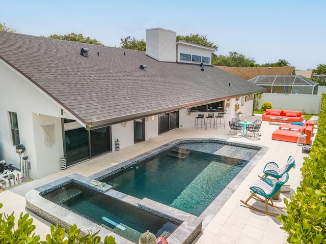 back of house featuring a bar, a swimming pool with hot tub, an outdoor living space, and a patio area