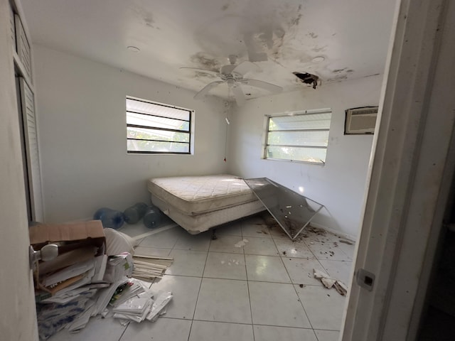 unfurnished bedroom featuring light tile patterned floors, a wall unit AC, and ceiling fan