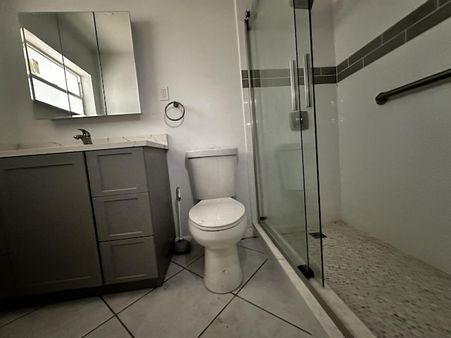 bathroom with toilet, vanity, tile patterned floors, and a shower with door