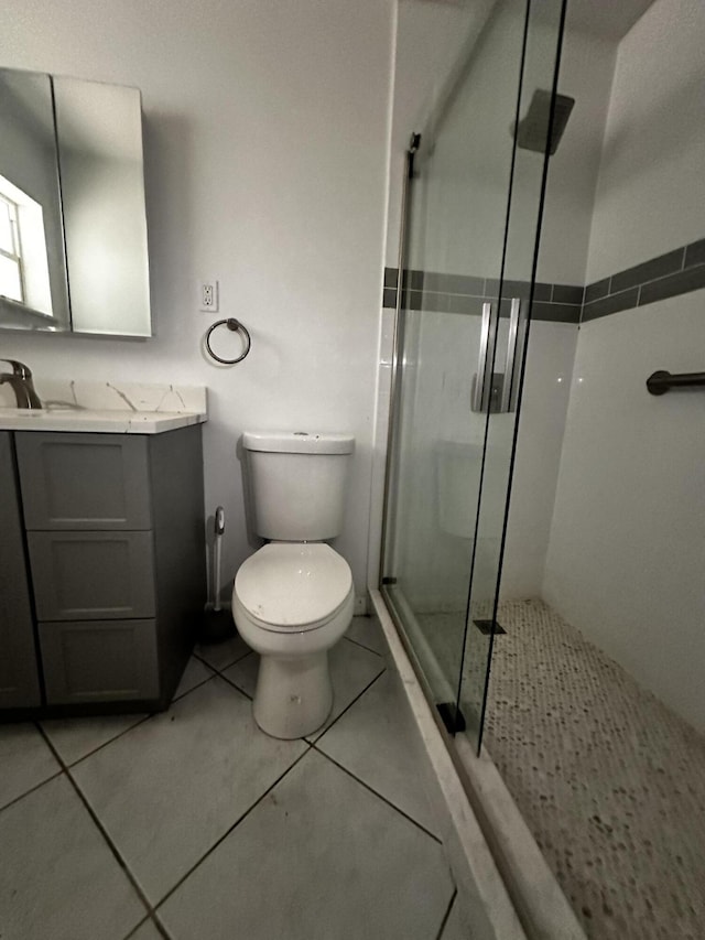 bathroom with toilet, vanity, tile patterned floors, and a shower with door