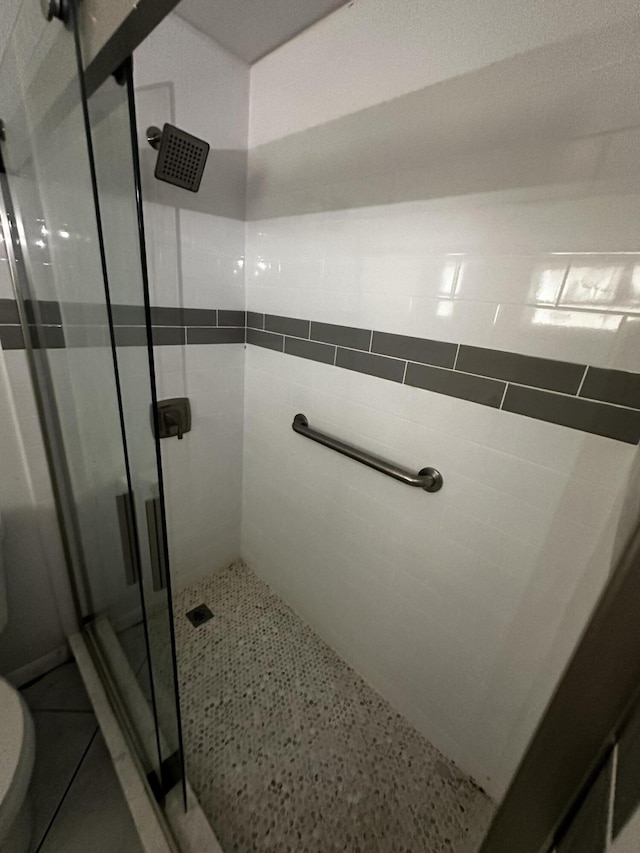 bathroom with toilet, tile walls, and a shower with shower door