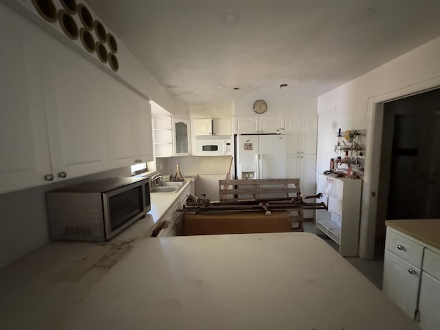 kitchen featuring white appliances, white cabinetry, and sink