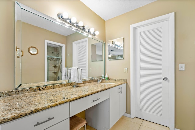 bathroom with a textured ceiling, vanity, tile patterned floors, and walk in shower