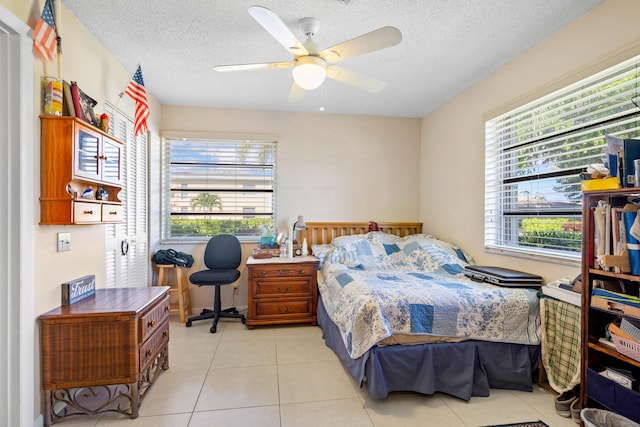 bedroom featuring ceiling fan, light tile patterned floors, and a textured ceiling