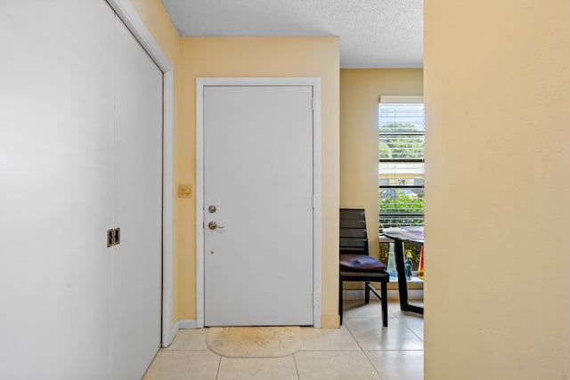 doorway featuring light tile patterned floors and a textured ceiling