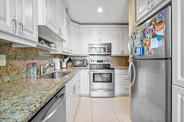 kitchen with white cabinetry, sink, a textured ceiling, light tile patterned flooring, and appliances with stainless steel finishes