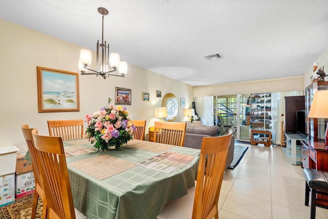 tiled dining area featuring a textured ceiling and an inviting chandelier