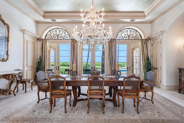 dining area with a chandelier, arched walkways, french doors, and a tray ceiling