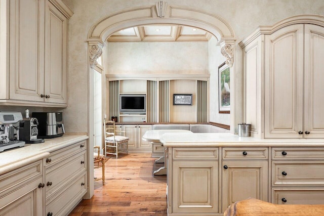 kitchen featuring beam ceiling, light countertops, cream cabinets, light wood-type flooring, and coffered ceiling