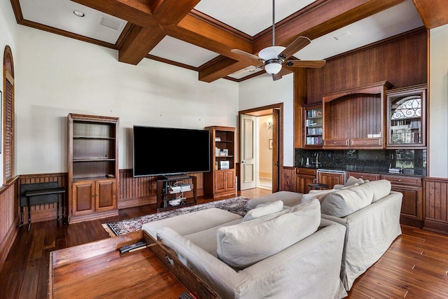 living room featuring a wainscoted wall, dark wood finished floors, coffered ceiling, and beamed ceiling